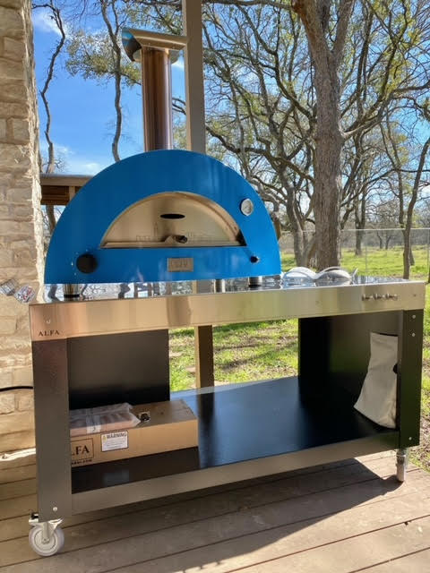 The fron view of the Beautiful prep table hoisting up the Limited Edition 2 Pizze Hybrid Gas wood Pizza Oven with Peel and Turner Kit - In Liquid Propane 