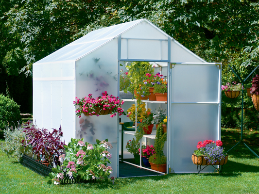 Outside view of 8' X 24' solexx garden master small greenhouse with flowers outside the greenhouse