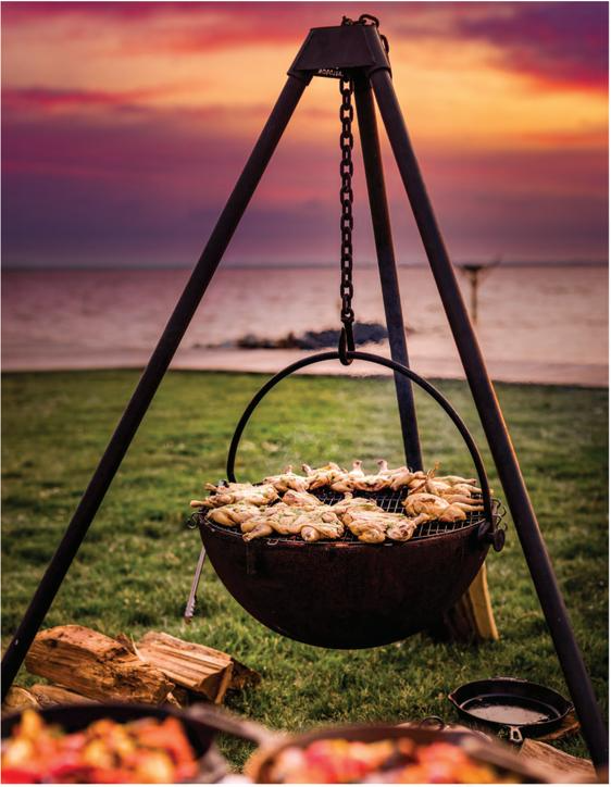 Tripod stand Wood Burning Fit Pit at ocean side, A chain Suspension Holding the Wood Burning Fire Pit with chickens on the top