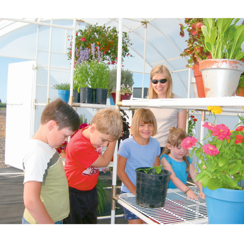 A woman and children standing inside solexx 16' x 20' outdoor greenhouse