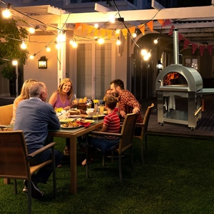 Family enjoying a meal outdoors with a Pinnacolo Premio pizza oven in the background