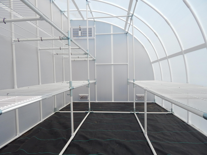 Inside of a solexx harvester small greenhouse which shows Doubled-tiered bench frame and single tier bench frame and a black polypropylene floor