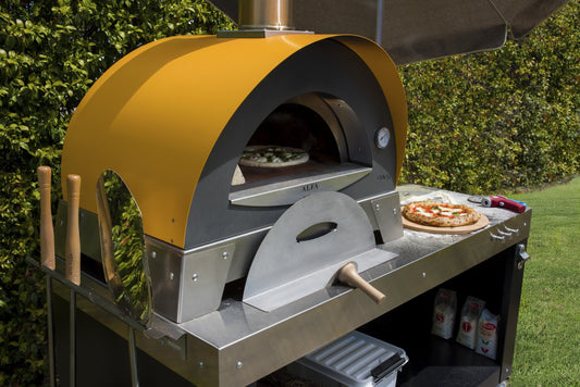 Outdoor Wood Pizza cooking with Italian Flair. This the Alfa Ciao on top the the large prep table. The True Italian pizza oven the Alfa Forno Ciao is a wood fired pizza oven for the backyard pizza enthusiast. This pizza oven you can add the cart, legs or just use your own backyard table. the base does not get too hot to be put on wood.